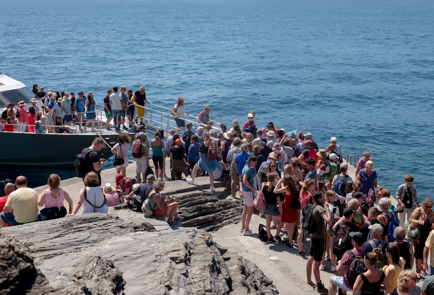 Tourists stream into Cinque Terre via train or from cruise ships docked at a nearby terminal.